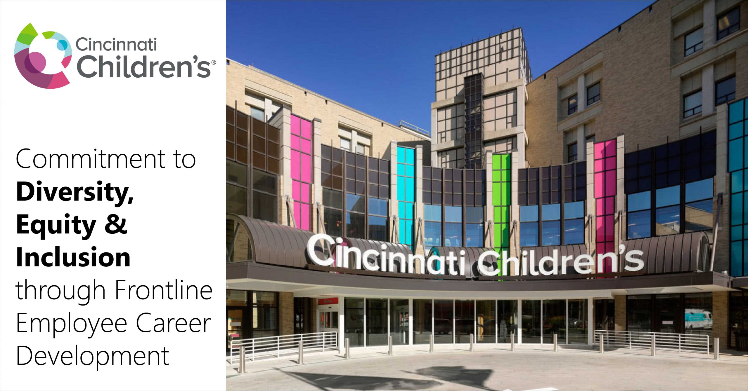 Cincinnati Children's Hospital Medical Center main entrance shown. The name of the hospital is in a curving arch. There are 4 banners of color running vertically (orange, blue, green, and red). The sky is a bright blue in the background. No people are shown.